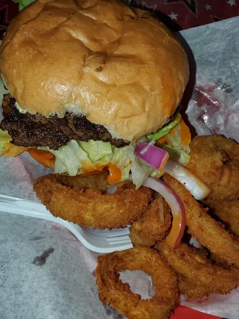 Smoked seasoned beef burger with crispy onion rings at Harper's BBQ Houston